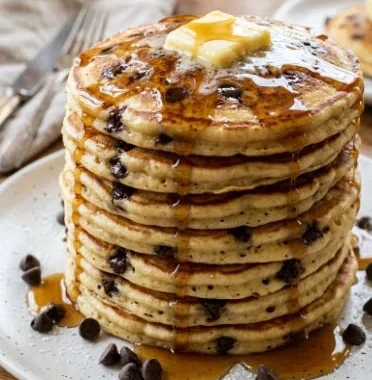 Delicious stack of chocolate chip pancakes topped with syrup and berries