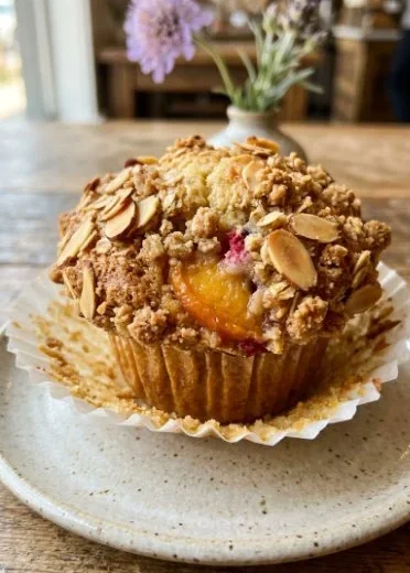 Freshly baked Peaches & Cream Muffins topped with almond crumble