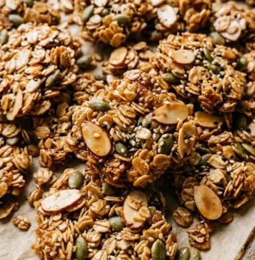 Bowl of tahini granola topped with fruits and nuts, a healthy snack option.
