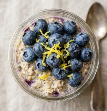 Blueberry lemon overnight oats in a bowl topped with fresh blueberries and lemon zest.