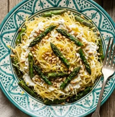 Plate of spaghetti squash with fresh asparagus garnished with herbs