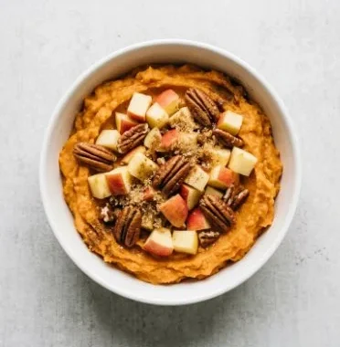Delicious Sweet Potato Breakfast Bowl topped with nuts and fresh fruits