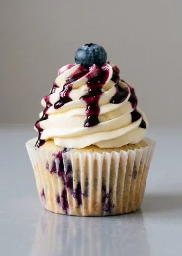 White chocolate blueberry cheesecake cupcakes with a creamy topping and fresh berries.